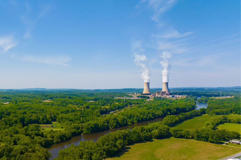 Two cooling towers off in the distance of a blue sky